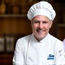 Portrait d'un chef pâtissier français souriant, en toque.